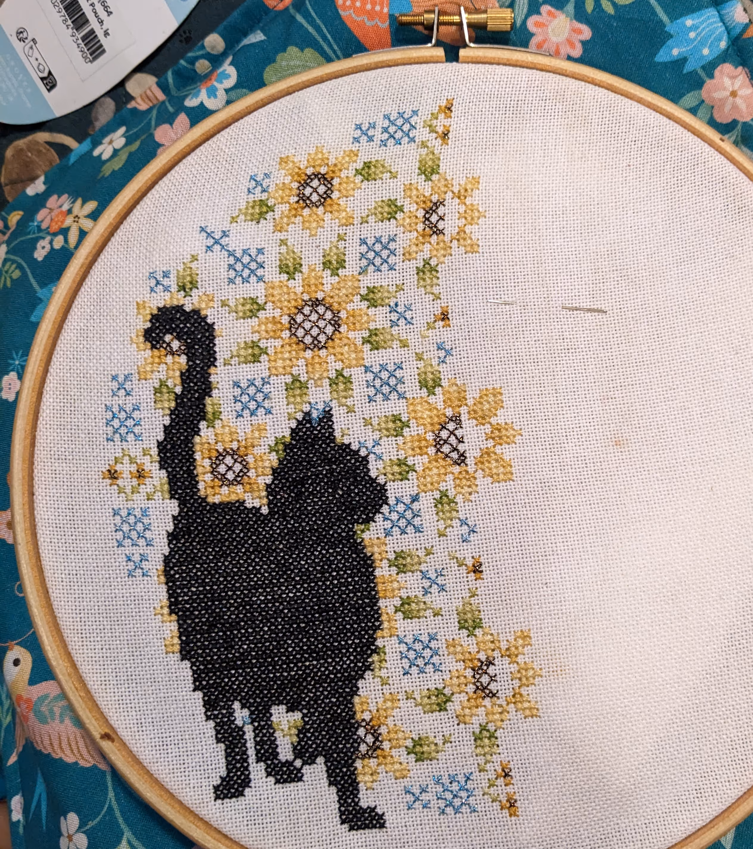 A black cat is featured in front of a backdrop of sunflowers