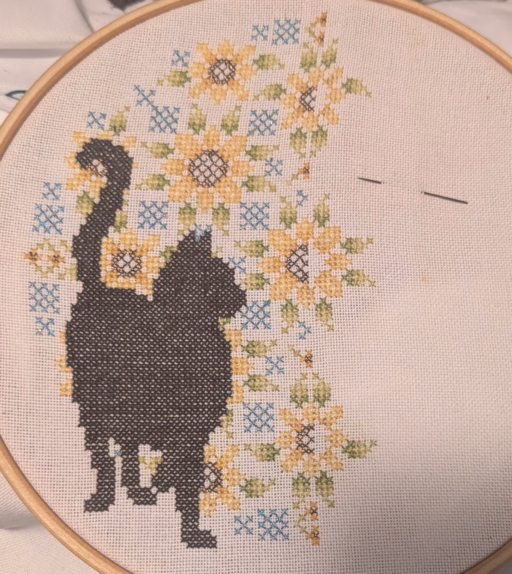 A black cat stands in the forground of a sunflower mandala