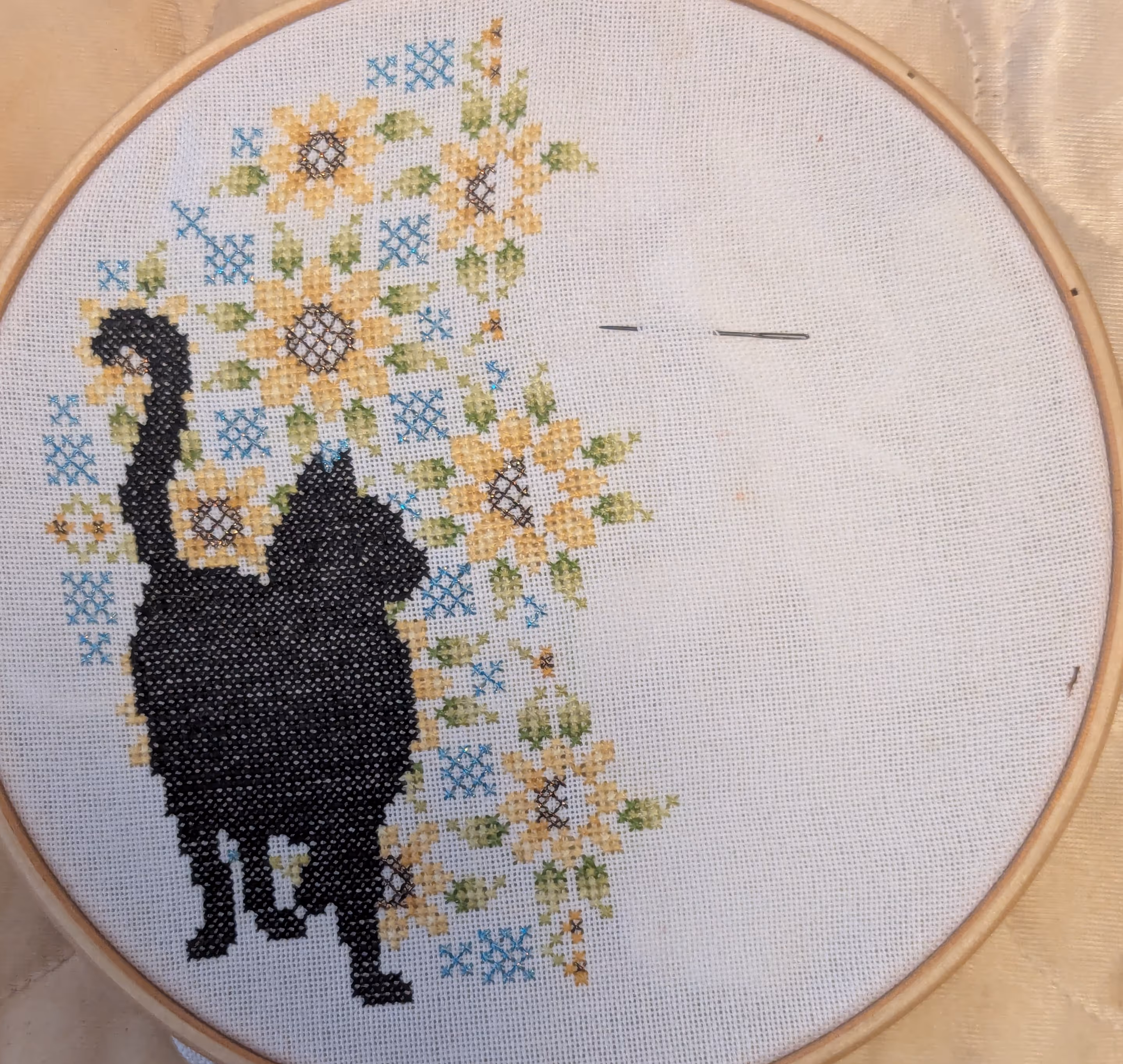 This cat is surrounded by sun flowers with metallic threads