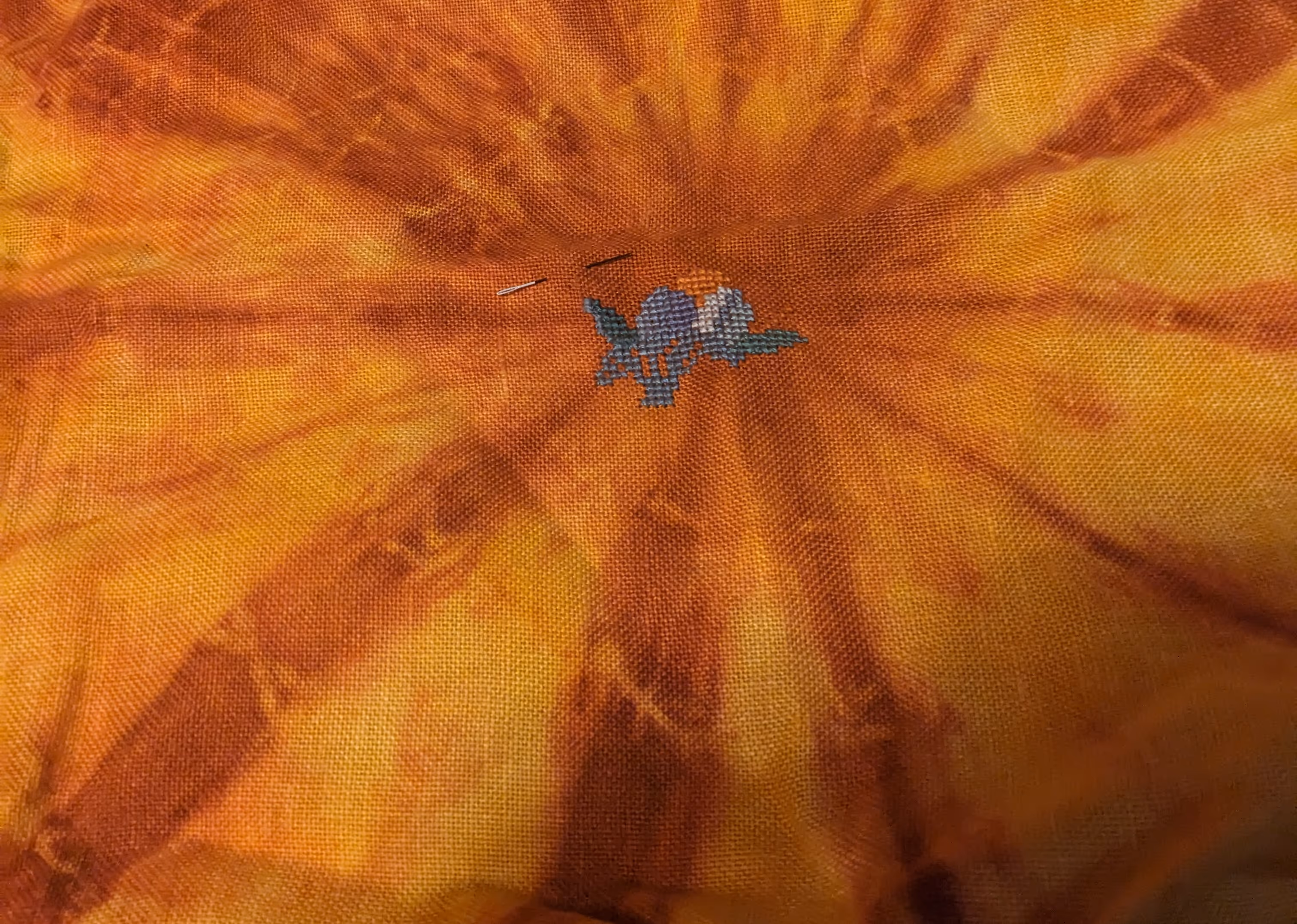 image of a cross stitch of a dragon's head in blues and orange