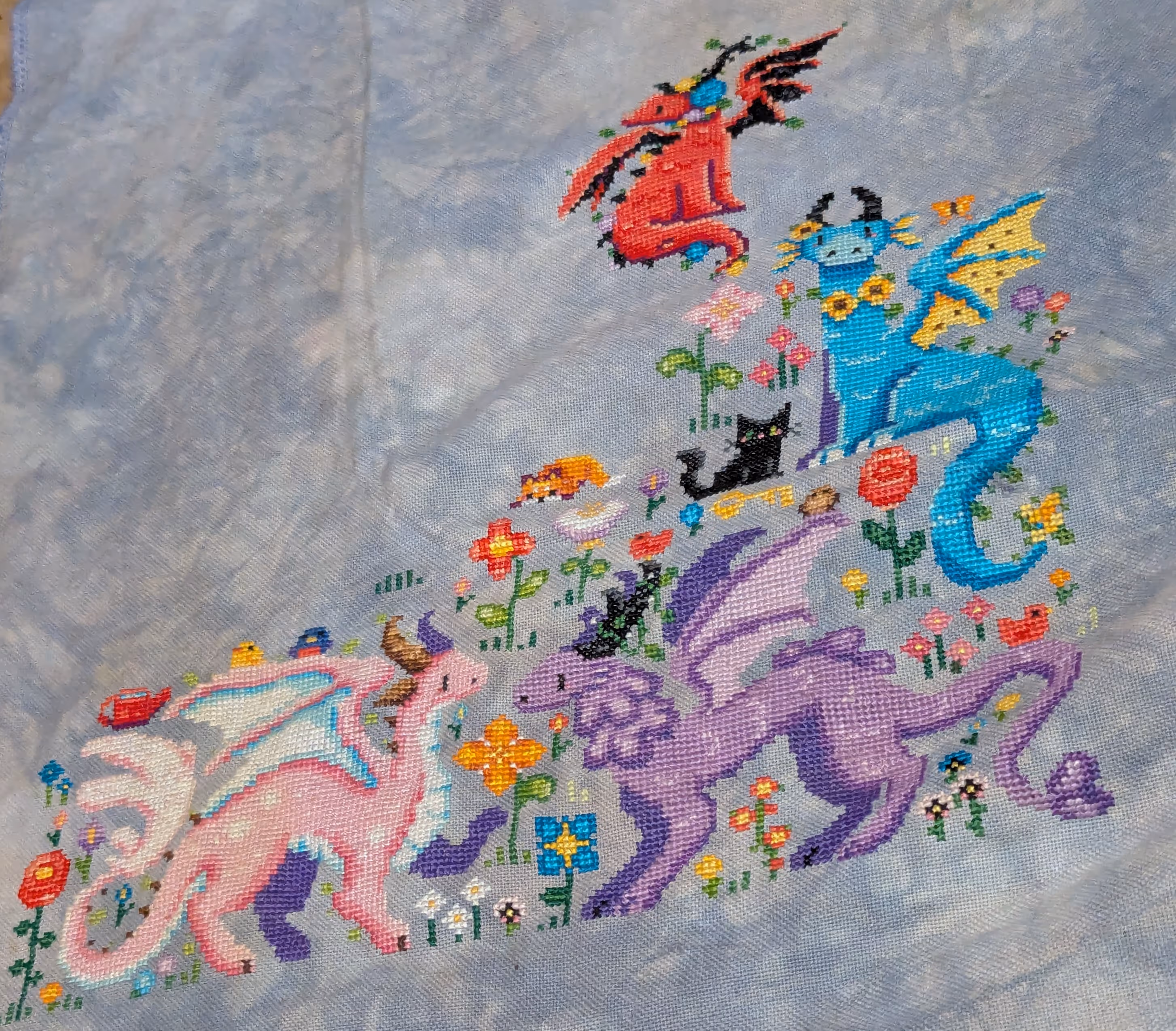 Four dragons in multiple colors frolic in a field with flowers and brids