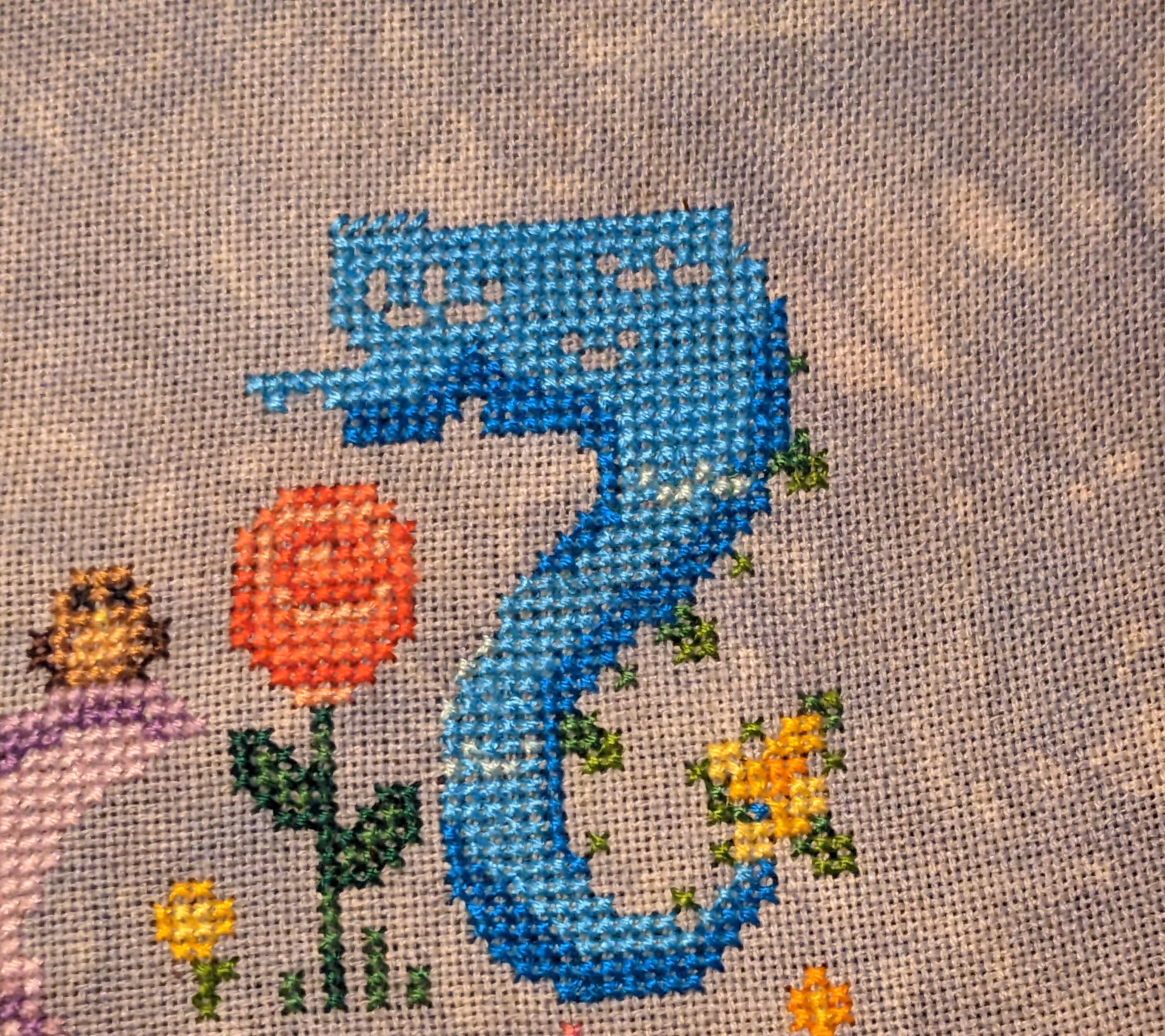 The tail of a dragon is shown in shades of blue and a yellow flower at the end