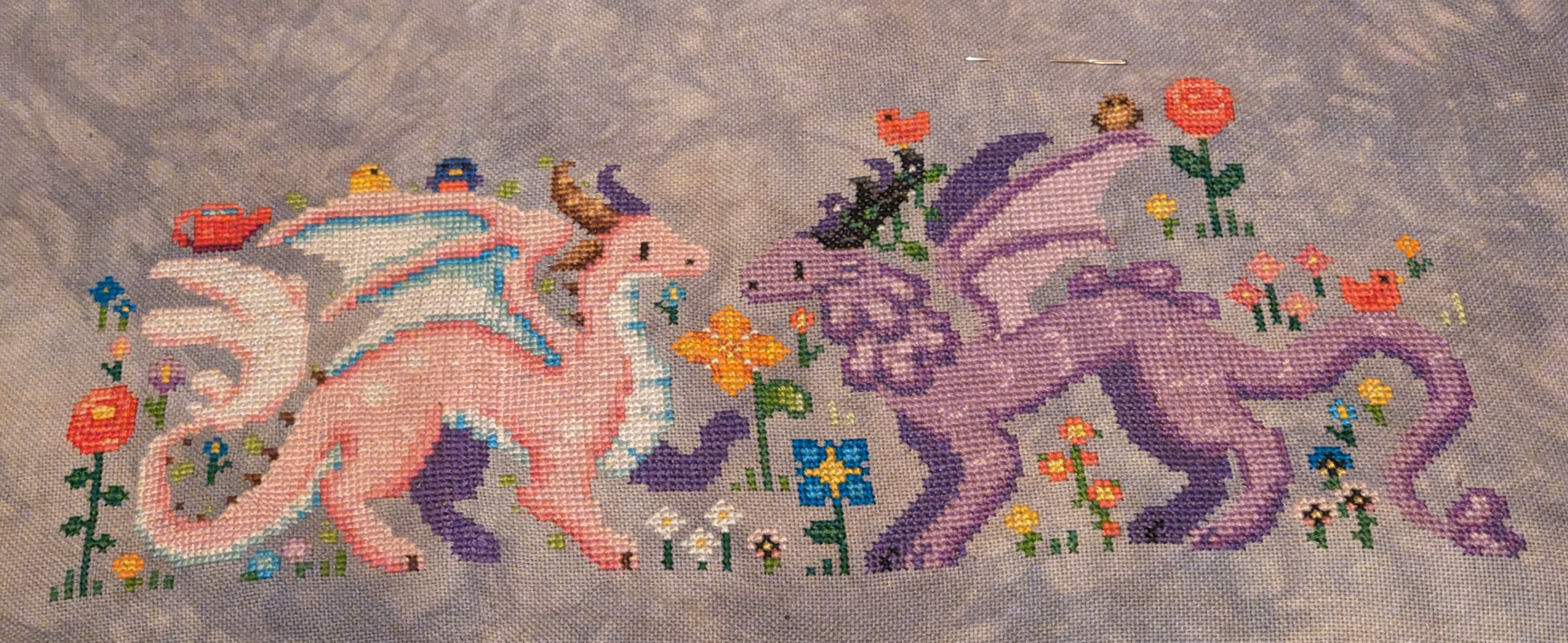 image of a pink dragon with white spots in honor of a cherry blossom and a purple dragon inspired by a wisteria flower in a meadow with grass, flowers, and birds