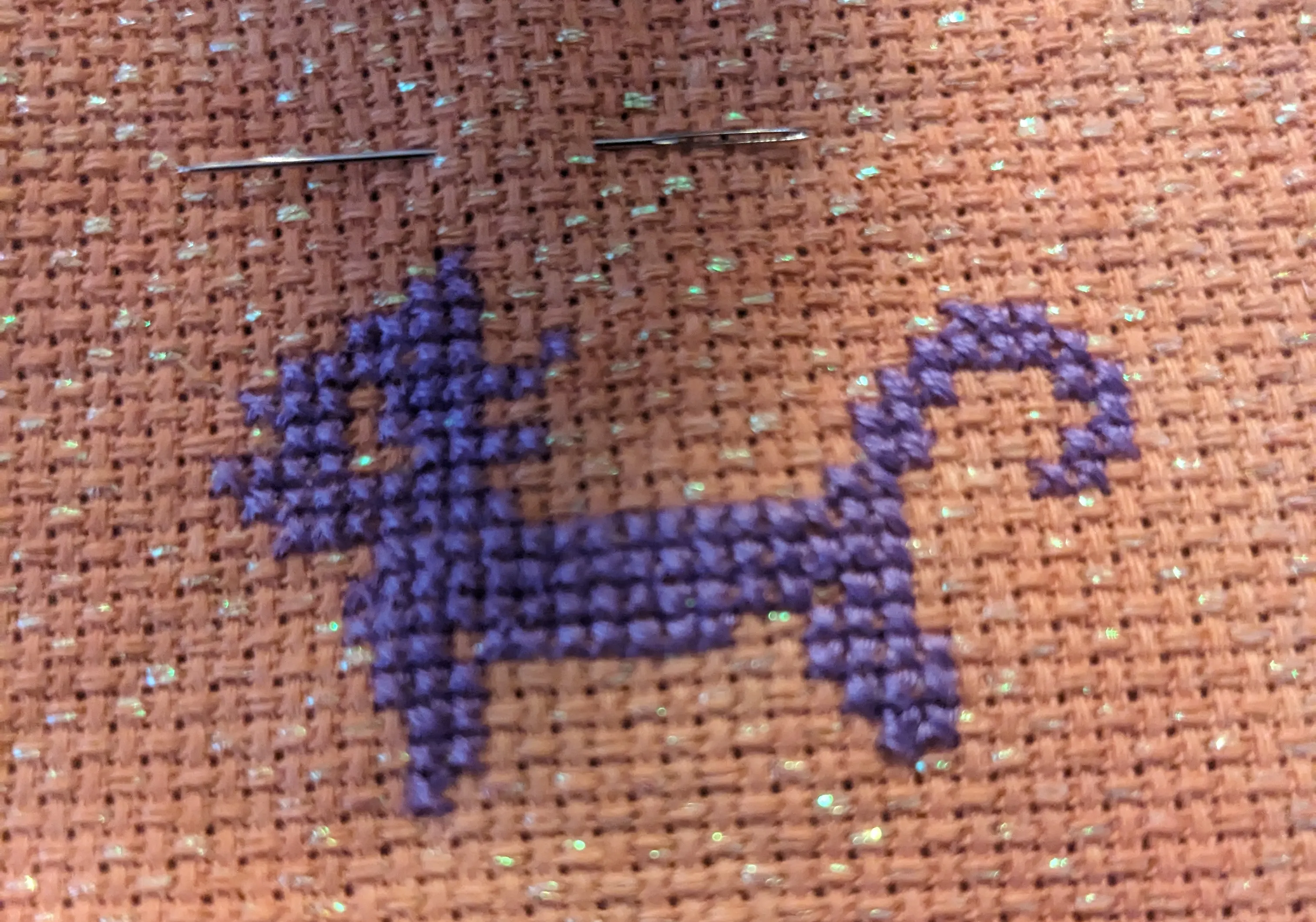 Image of a black cat in cross stitch on an orange opalescent fabric