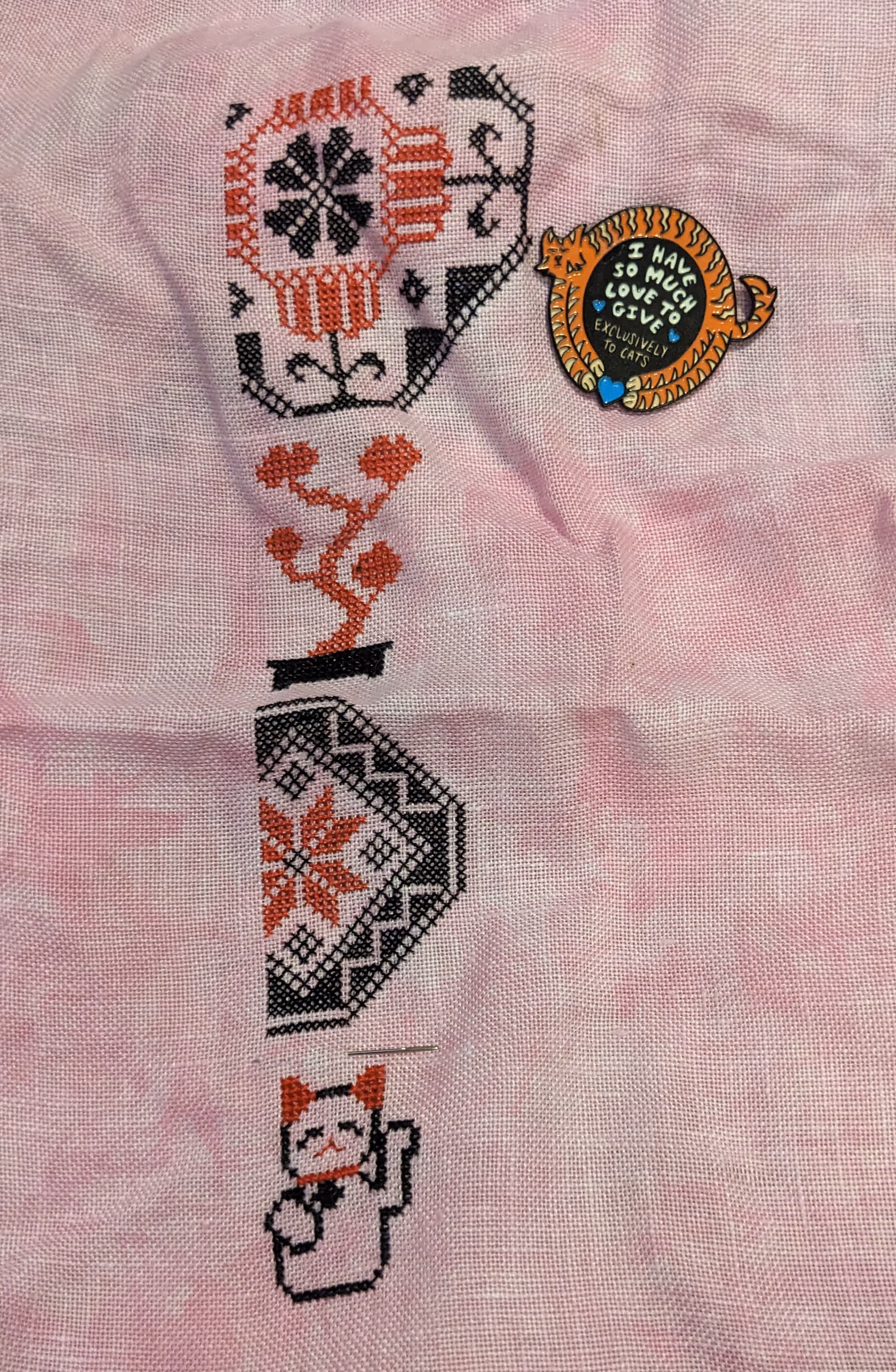 A Quaker Sampler with Japanese themed motifs in black and red on a cherry blossom pink fabric