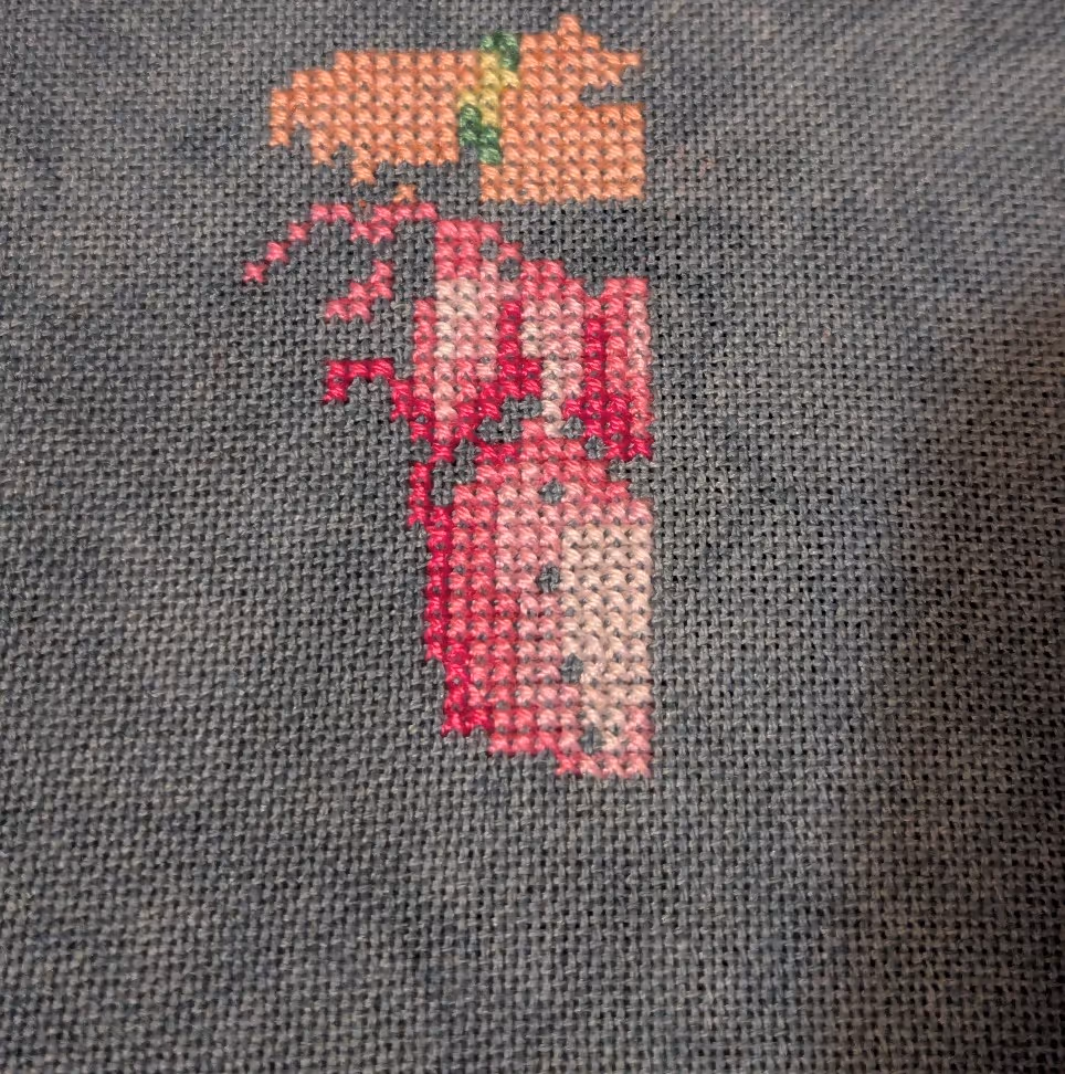 The top of a dress in shades of pink with a green strap