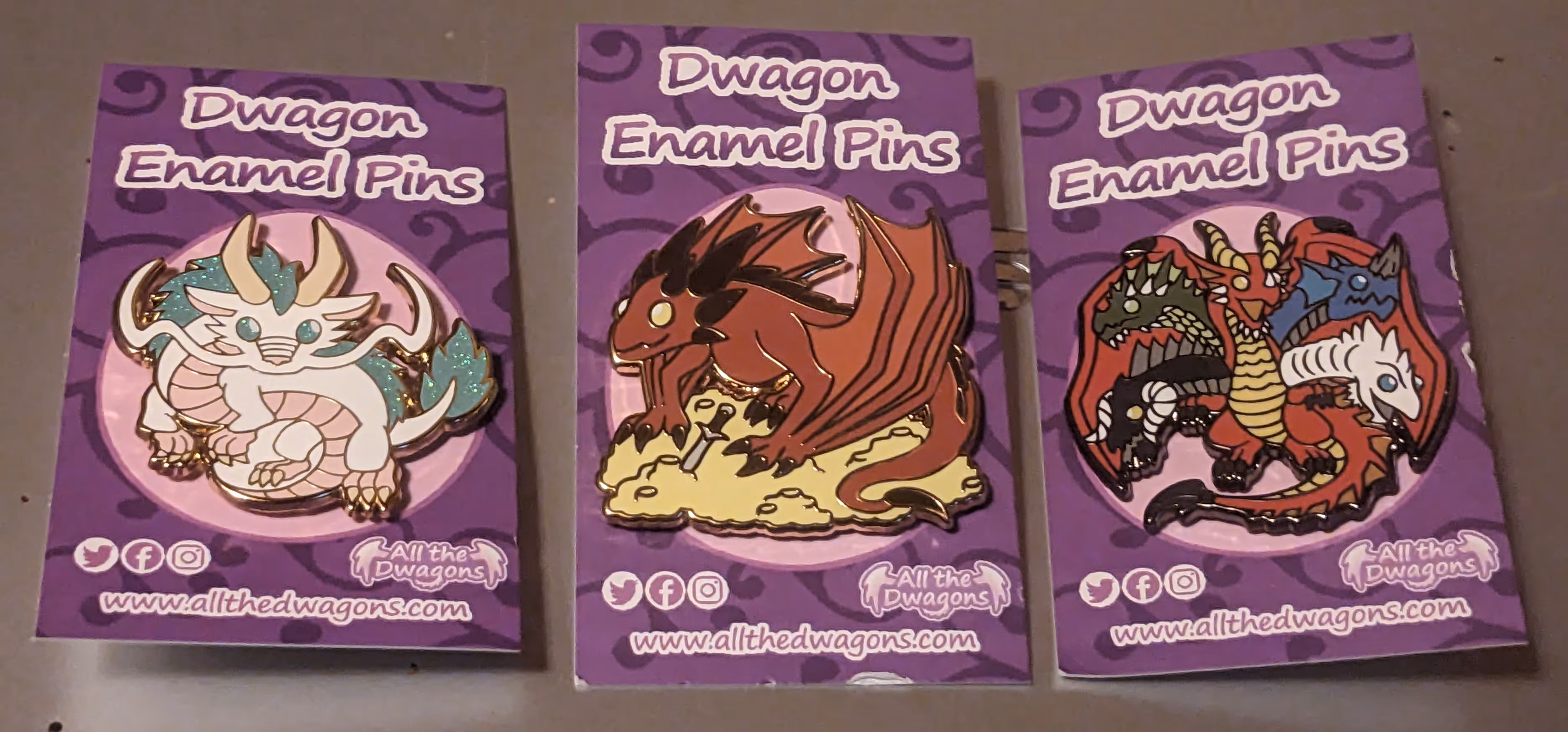 image of three enamel pins featuring Haku, Smaug, and Tiamat