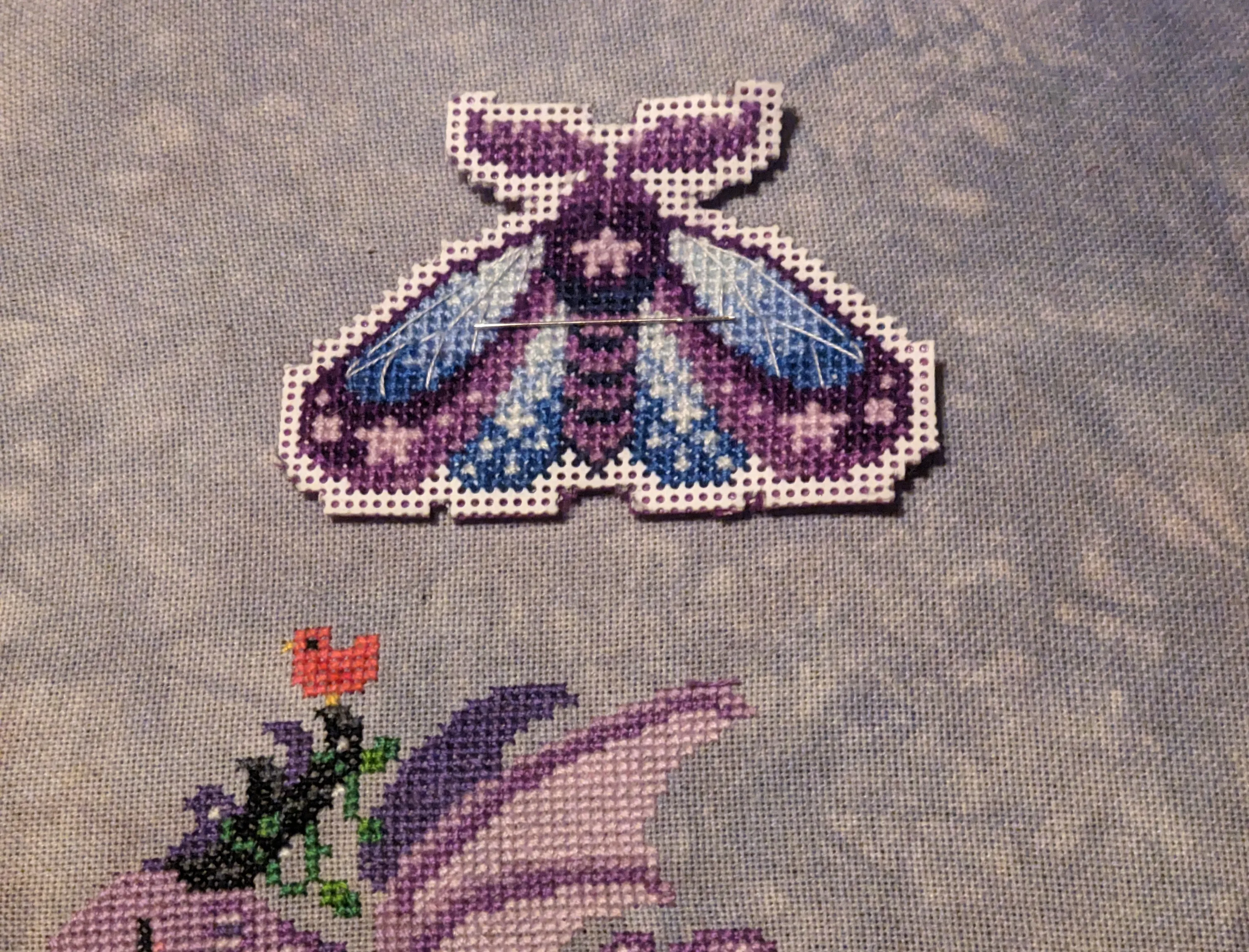 Image of a moth in shades of purple and blue with pink stars