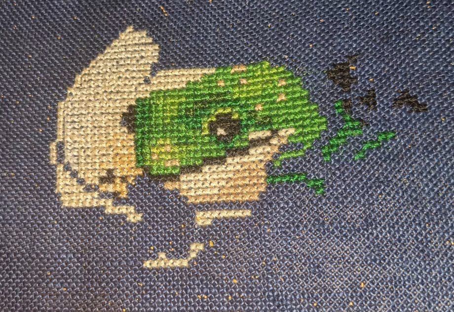 A frog face is shown in shades of green surrounded by the white color of a tea cup