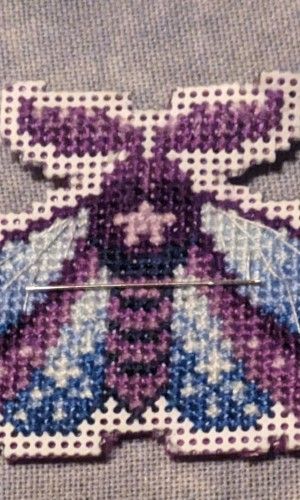 A small moth whose wings are colored in blues and purples shines like a jewel