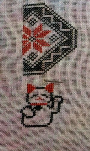 A Quaker Sampler featuring motifs inspired by the traditions of Japan in black and red thread on a cherry blossom pink fabric