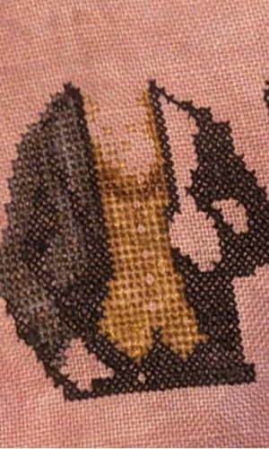 A partial cross stitch of a crow gentleman holding a ladies hand