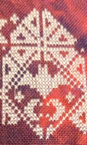 A geometric pattern with bat motifs in white thread on a gothic red fabric