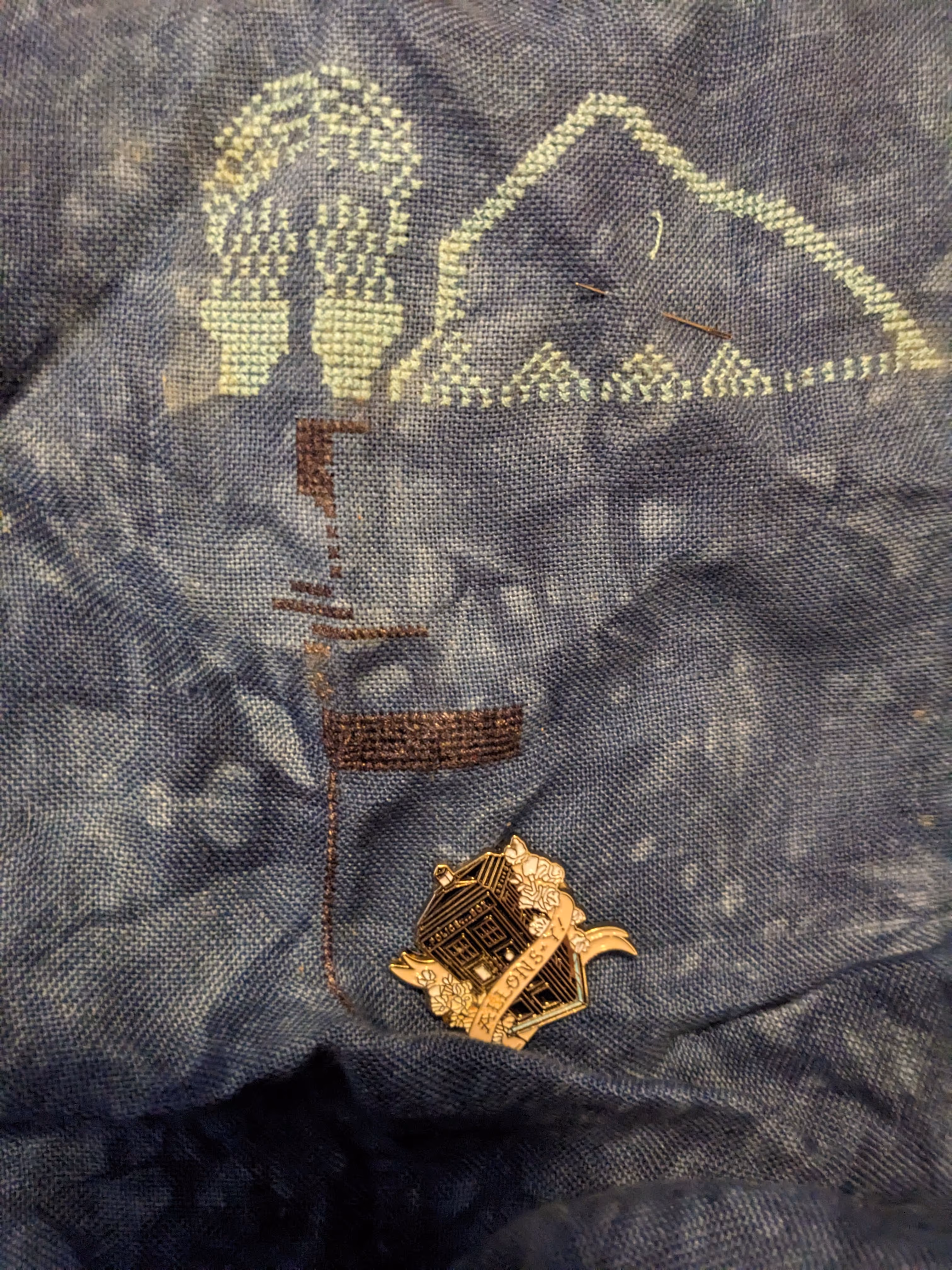 A weeping angel is featured at the top of this Doctor Who themed cross stitch on Tardis blue fabric